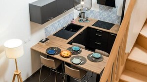 Une cuisine compacte dotée d’un îlot central, d’un évier et d’un petit coin repas avec des chaises.