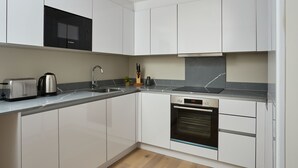 Une cuisine moderne avec des meubles blancs, un four à micro-ondes Bosch, un grille-pain, un évier et un lave-vaisselle.