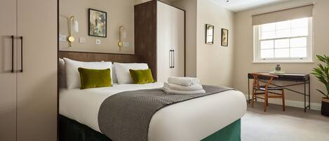 A neatly arranged bedroom with a bed, a desk, and a chair.