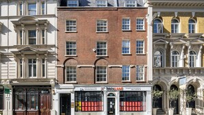Une rangée de bâtiments historiques présentant un mélange de styles architecturaux, notamment un bâtiment en briques doté de grandes fenêtres et un bâtiment blanc aux détails ouvragés.