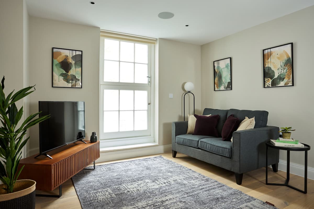 A modern living room with a grey sofa, a flat-screen TV, and artwork on the walls.