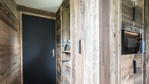 Un intérieur en bois avec une porte noire, des étagères et un four encastré.