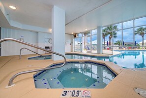 Une piscine intérieure d’une profondeur de 1,14 mètre (3 pieds et 9 pouces), avec un panneau indiquant qu’il est interdit de plonger, et offrant une vue sur les palmiers à l’extérieur.