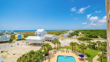 A beachfront property with a swimming pool, multiple buildings, and a clear view of the ocean.