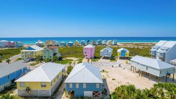 A coastal area with colorful houses, some elevated on stilts, and a clear view of the ocean.