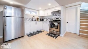 A modern kitchen with white cabinets, stainless steel appliances, and a black and white backsplash.