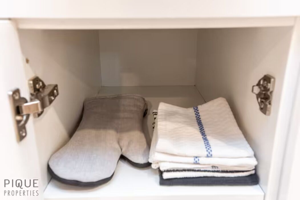 A white cabinet with a grey cushion and folded towels.