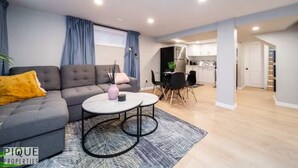 A modern living room with a grey sofa, a round coffee table, and a dining area with a black table and chairs.