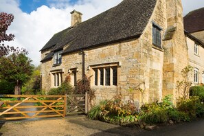 A stone building with a traditional design, featuring a wooden gate and a well-maintained garden.