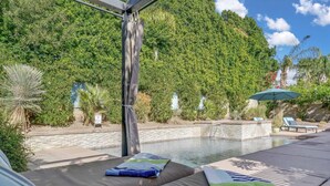 A poolside area with lounge chairs and a covered seating area.