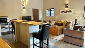 A spacious living area with a kitchen island, a dining table, and a sofa set. - Leadwood Tree Safari Lodge  (Hoedspruit)