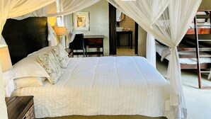 A room with a bed under a canopy, a desk with a chair, a mirror, and a small table with towels. - Leadwood Tree Safari Lodge  (Hoedspruit)