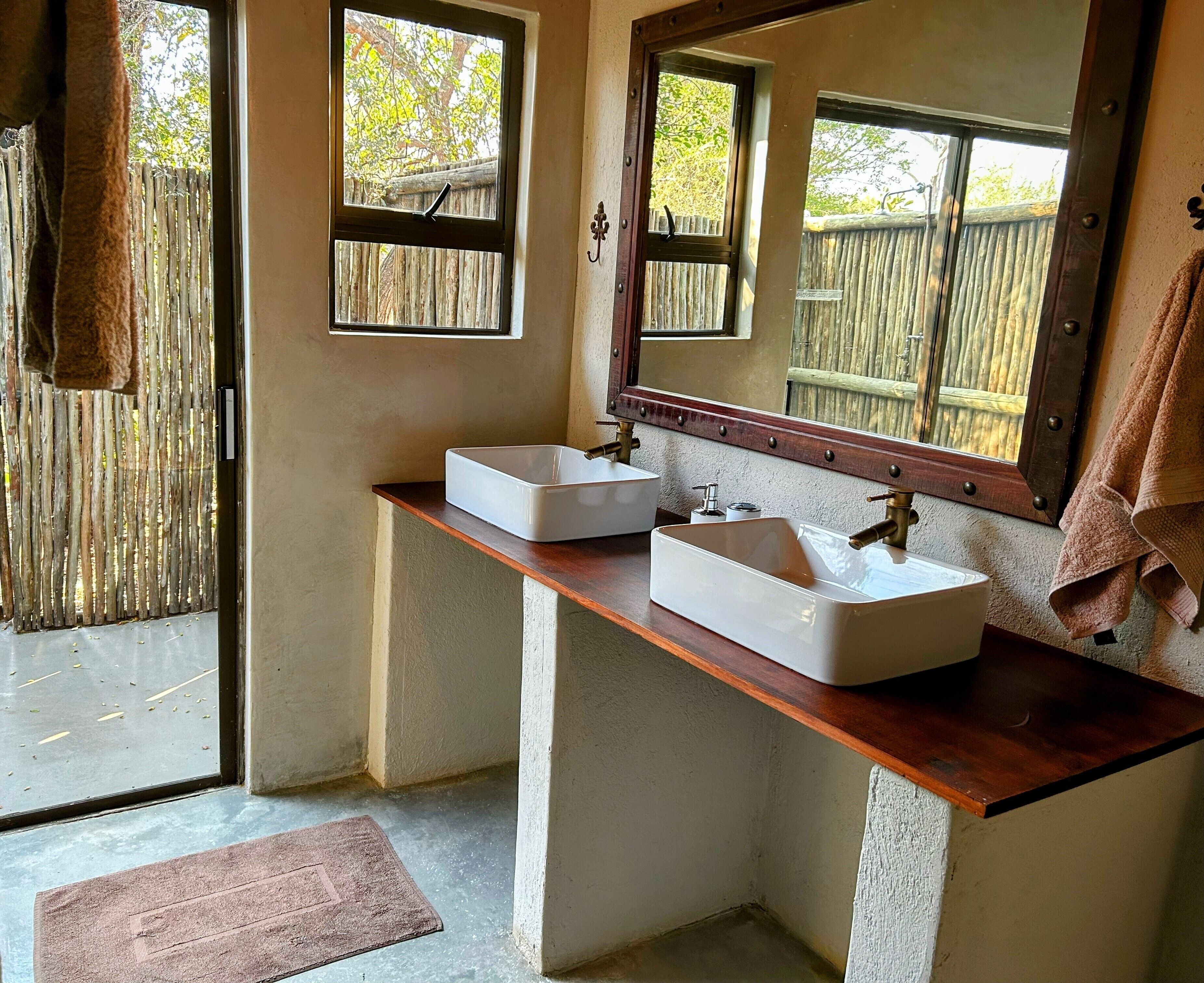 A bathroom with two white sinks, wooden countertop, and a large mirror.