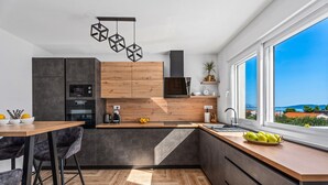 A modern kitchen with a wooden countertop, dark cabinets, and a large window offering a view of the sea. - Villa Lea with 4 bedrooms, 40sqm pool, Hot-Tub, 2km from the beach (Kastel Novi)