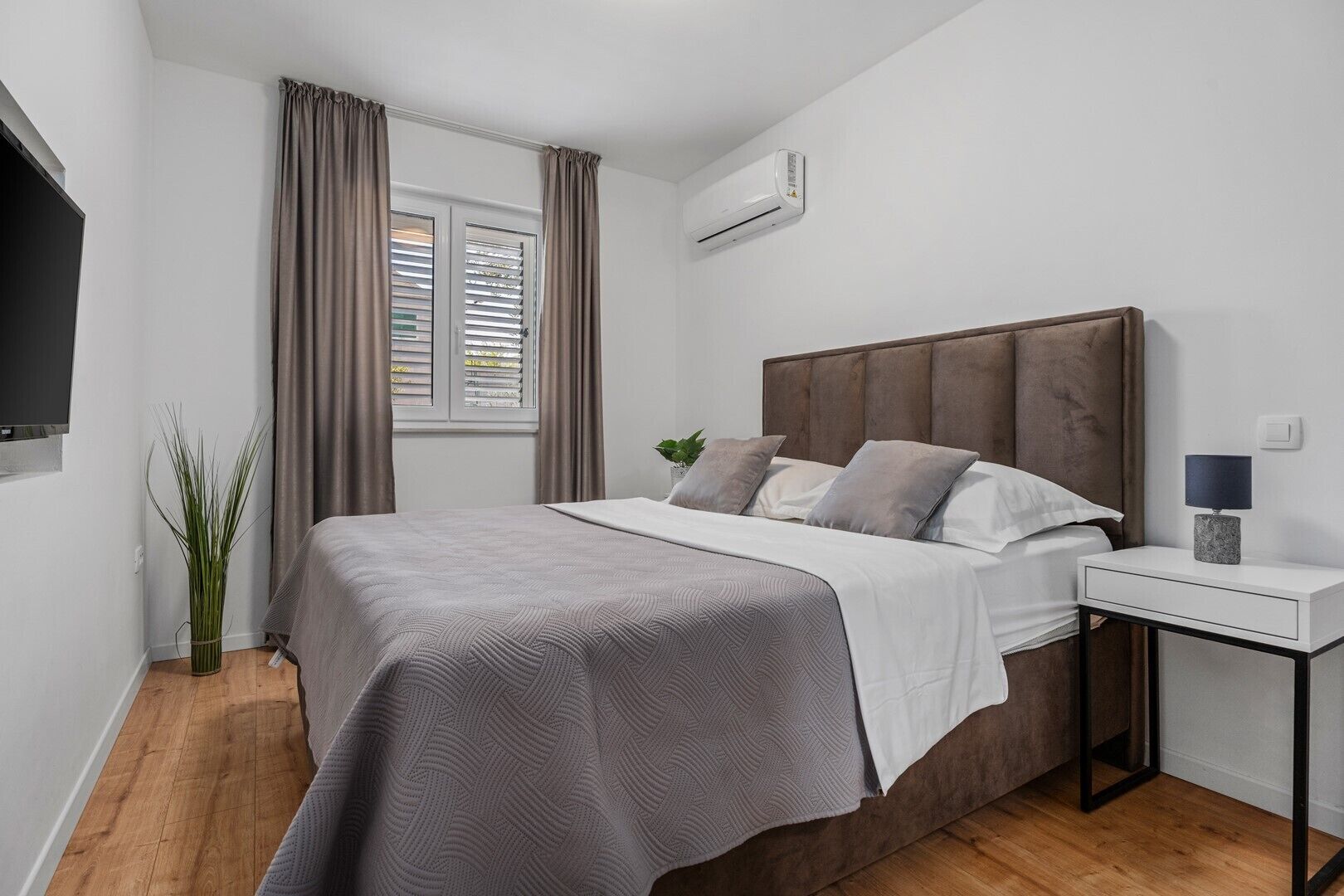 Une chambre moderne équipée d’un lit, d’une table de chevet et d’un appareil de climatisation.