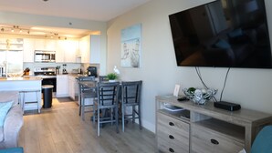 Una cocina moderna con comedor, un televisor de pantalla plana en la pared y un escritorio de madera con cajones.