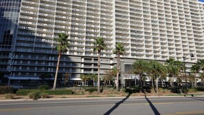 Un hotel grande con varias plantas, balcones y palmeras en la fachada.