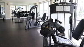 Un gimnasio con varias máquinas de ejercicio, incluyendo una máquina para extensión de piernas y mancuernas.