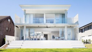 A modern two-story house with a balcony, large windows, and a flat roof.