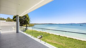 A balcony with a clear view of a calm lake, boats, and distant hills.