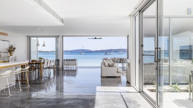 A modern interior with a dining area, seating, and a view of the sea.