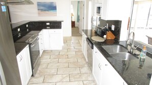 A compact kitchen with white cabinets, a black countertop, and a tiled floor.
