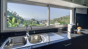 Cucina con lavello in acciaio inossidabile e un'ampia finestra che si affaccia su un paesaggio urbano e aree verdi.