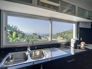 A modern kitchen with a large window offering a city view. - Santa Rita House by Atlantic Holiday (Funchal)