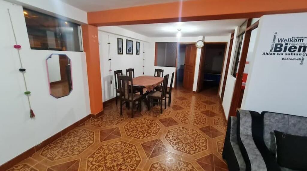 A dining area with a table and chairs, a decorative mirror, and a patterned floor.