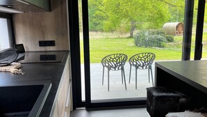 Eine moderne Küche mit einem großen Fenster, einem Essbereich mit zwei Stühlen und einem kleinen Hocker.