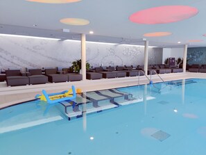 Una piscina con sillas de descanso y zona ajardinada junto a la piscina.