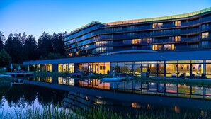 A multi-story hotel with a reflective pool, outdoor seating, and a forested backdrop. - Hotel AVIVA make friends - Singles only (Sankt Stefan-Afiesl)
