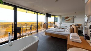 A modern bedroom with a large bed, a bathtub, and a balcony with a view. - Hotel AVIVA make friends - Singles only (Sankt Stefan-Afiesl)