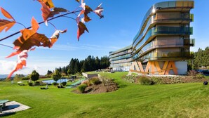 A modern building with a curved facade, a large 'A' logo, and a well-maintained lawn with outdoor seating. - Hotel AVIVA make friends - Singles only (Sankt Stefan-Afiesl)