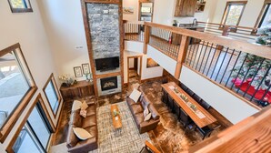 A spacious living area with a stone fireplace, wooden beams, a large sofa, and a dining table. - Incredible Craftsman Style Spacious Lodge Walking Distance to Clubhouse! (Lead)