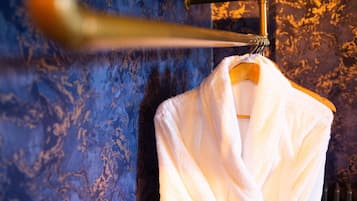 Una toalla blanca colgada de un perchero de madera frente a una pared azul con textura.