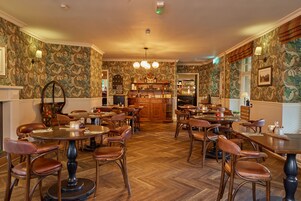 Un restaurante con suelo de madera, mesas redondas y sillas de cuero.