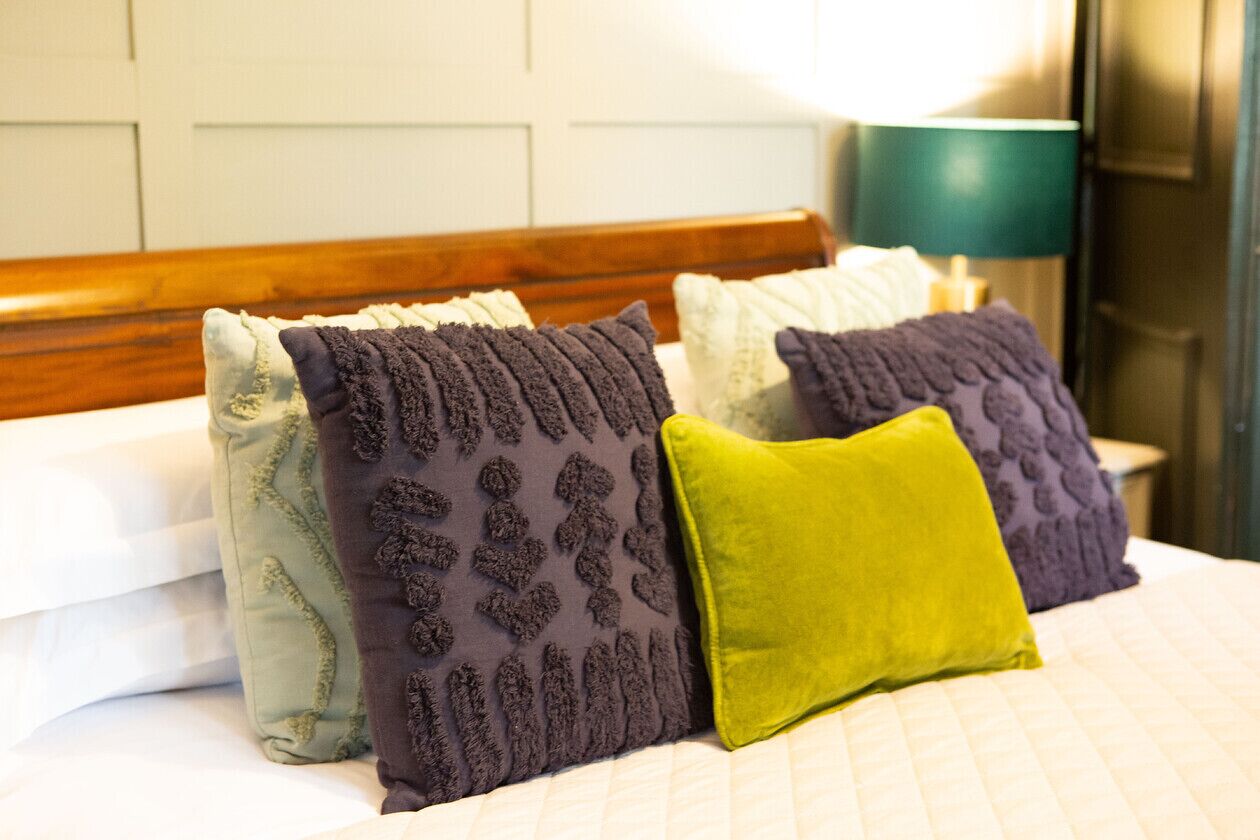 Una cama con muchos almohadones de distintos colores y texturas.