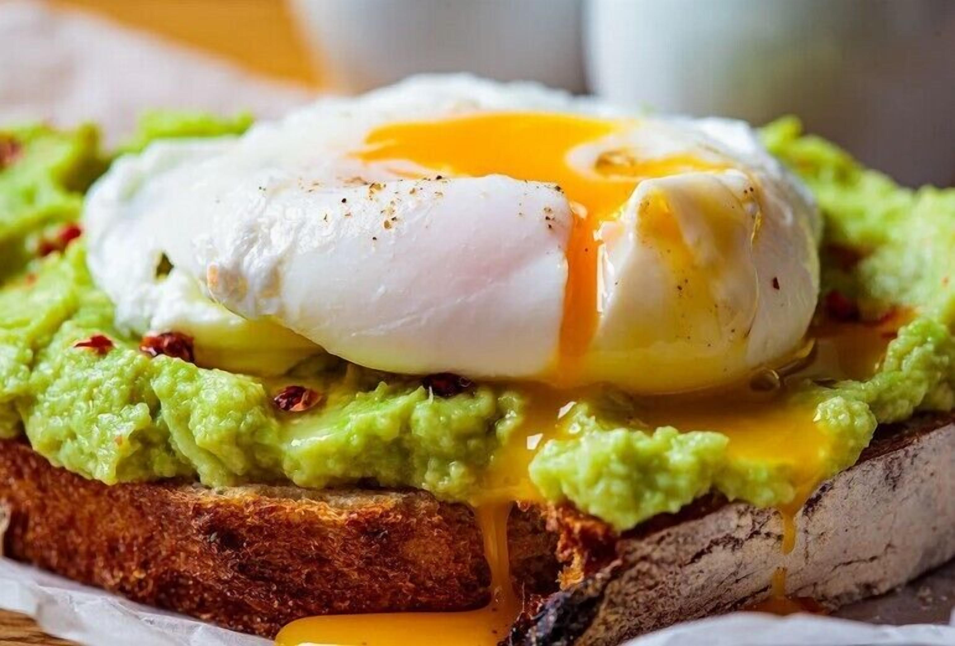 A breakfast dish with a poached egg on toast topped with avocado.