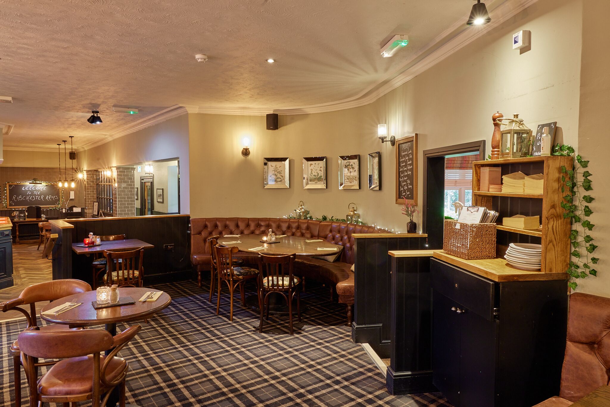 A restaurant with a checkered floor, wooden furniture, and framed artwork on the walls.
