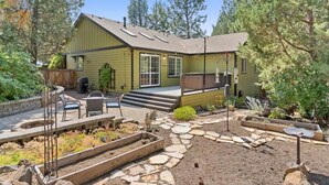 A house with a patio, outdoor seating, and raised garden beds.