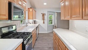A kitchen with wooden cabinets, a stainless steel stove, and a white countertop.