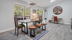 A dining area with a glass table, wooden chairs, and a patterned rug.