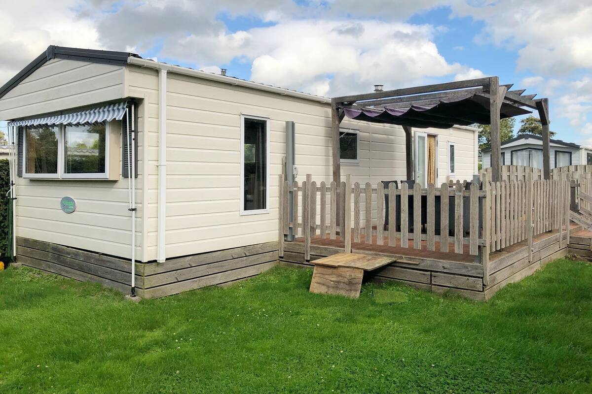 A mobile home with a small deck and a fenced area.