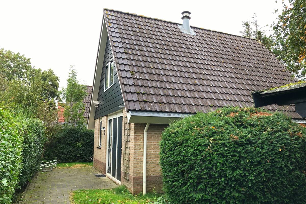 A house with a tiled roof, a brick exterior, and a paved pathway leading to the entrance.
