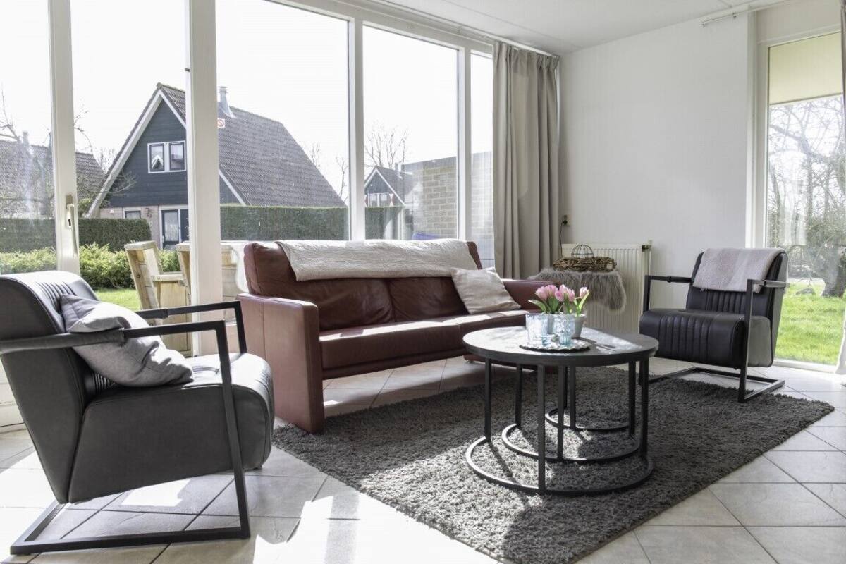 A modern living room with a brown leather sofa, a black armchair, and a round coffee table.