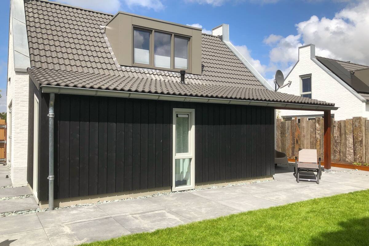 A house with a black exterior, a tiled roof, a window, and a door.