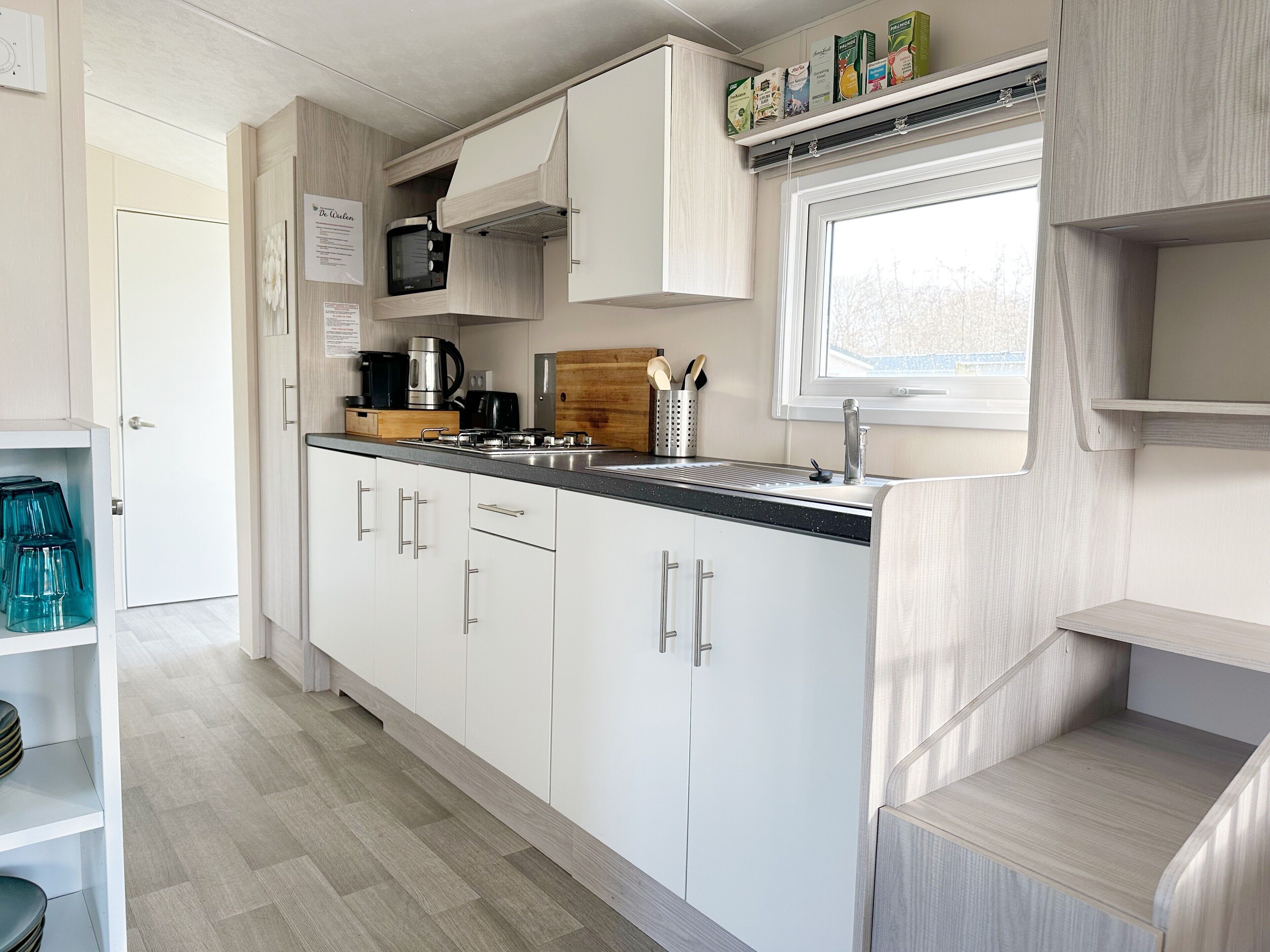 A compact kitchen with white cabinets, a stainless steel sink, and a window above the countertop.