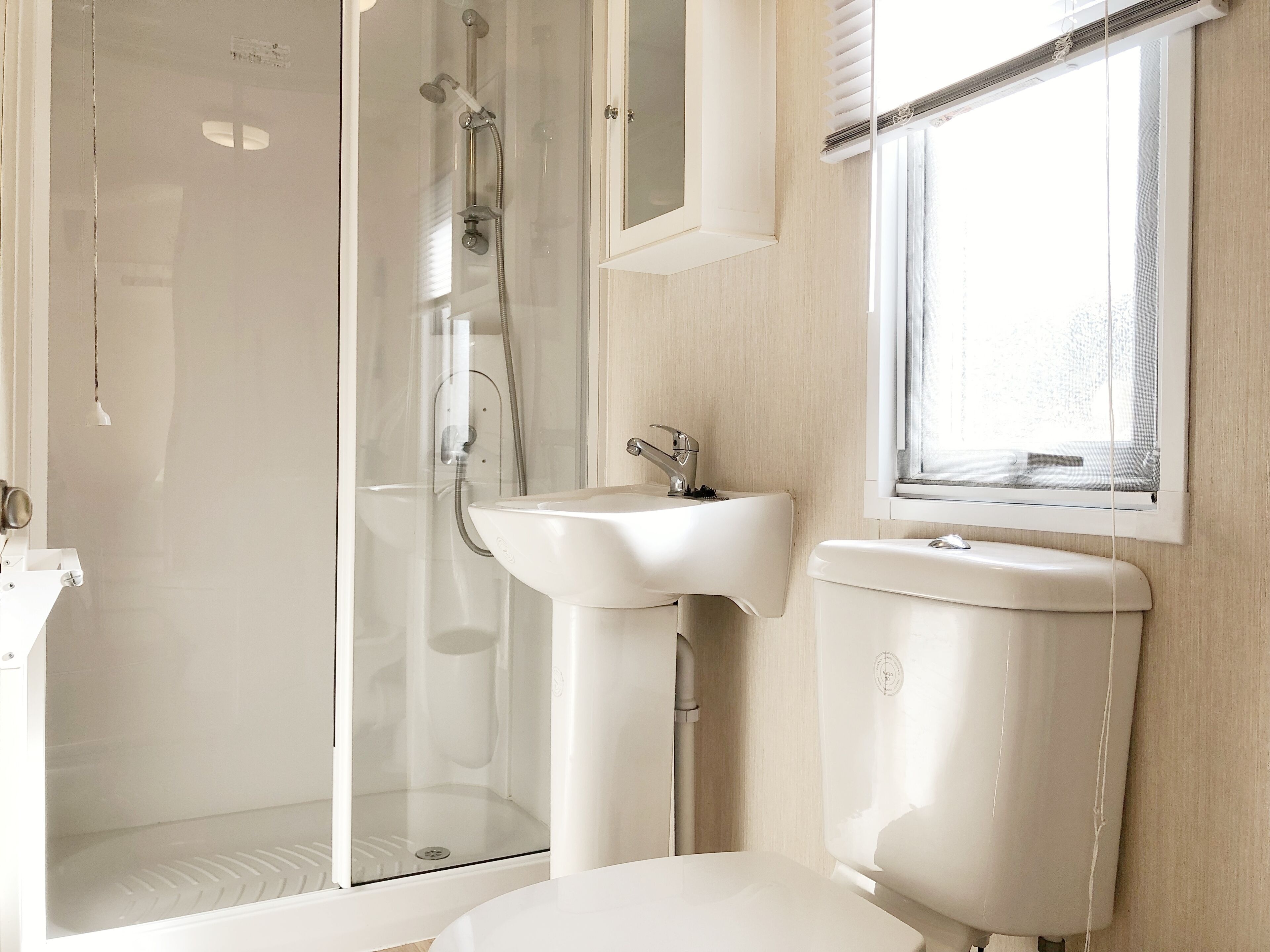 A bathroom with a glass-enclosed shower, a sink, and a toilet.