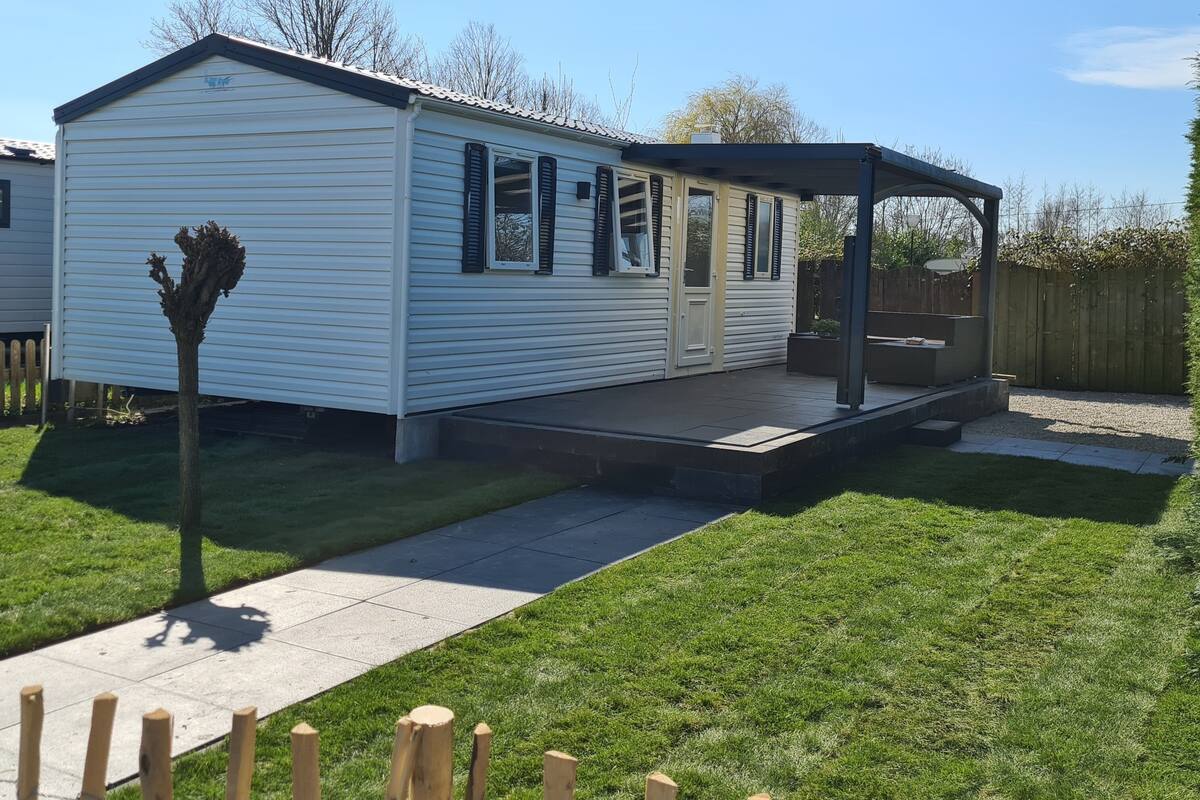 A single-story mobile home with a covered porch and a fenced yard.